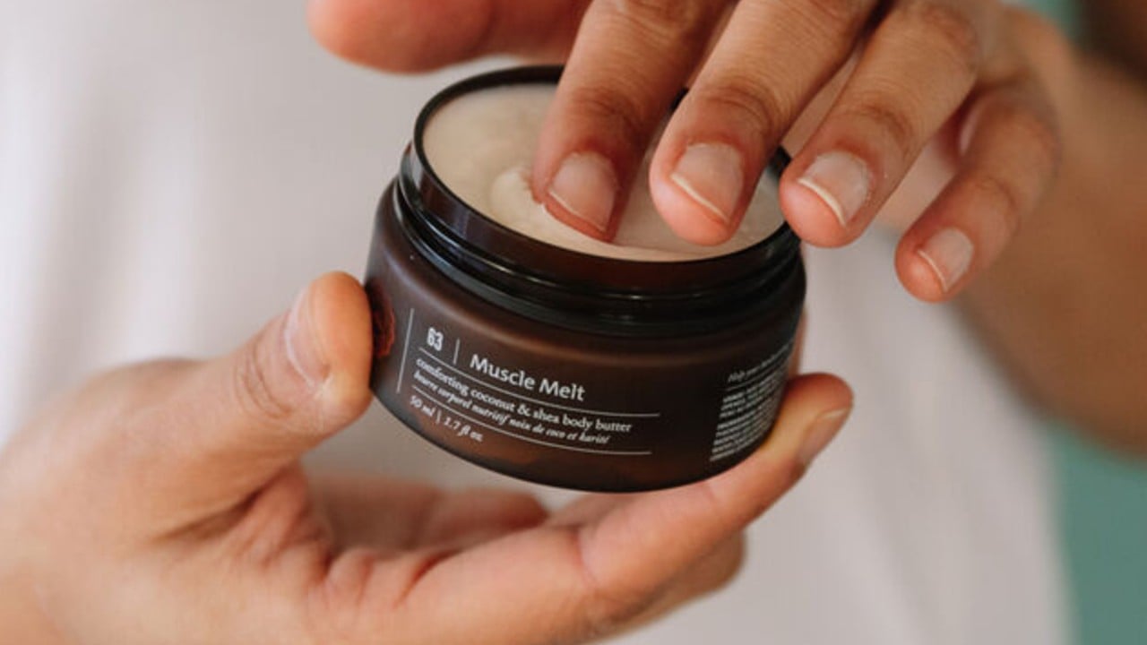 hands dipping into jar of saje muscle melt body butter